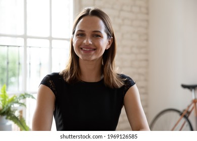 Smiling Beautiful Young 30s Woman Looking At Camera, Posing In Modern Office. Confident Businesswoman Holding Distant Video Call Zoom Meeting With Partners, Communicating Online At Workplace.