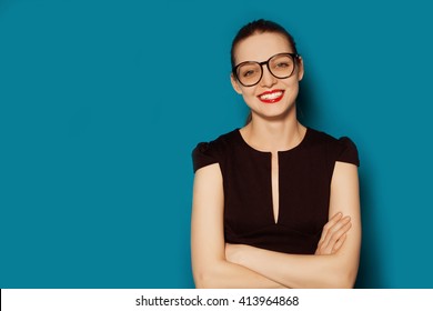 Smiling Beautiful Young Woman In Glasses. Business Studio Portrait On Blue Background 