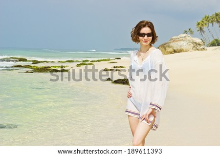 Smiling beautiful young woman sunbathing and posing on the beach. Horizontal image