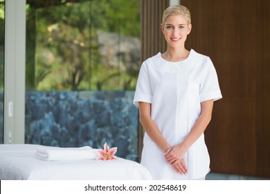 Smiling Beauty Therapist Standing Beside Massage Towel At The Spa