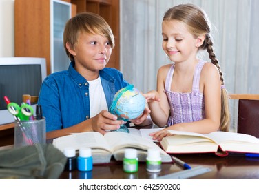 Smiling Big Brother Helping Little Girl To Do Homework At Home