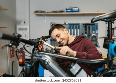 Smiling bike mechanic while manipulating the handlebar of an electric mountain bike with a ratchet - Powered by Shutterstock