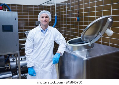 Smiling biologist leaning against storage tank in the factory - Powered by Shutterstock