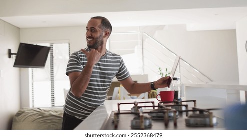 Smiling biracial man using tablet in kitchen. enjoying staying at home in self isolation in quarantine lockdown. - Powered by Shutterstock