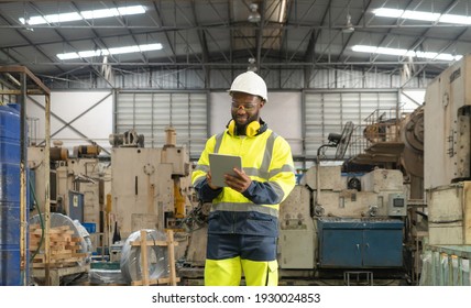 Smiling black African American man, an engineer or worker using a tablet device in manufacturing factory with machine engine production, technology in operation in industry plant in warehouse - Powered by Shutterstock