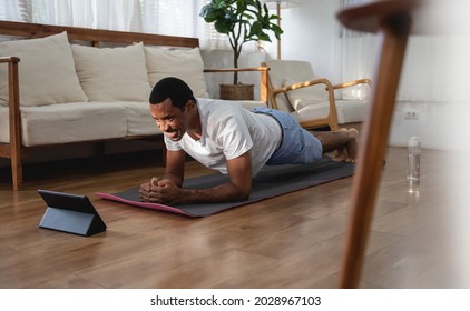 Smiling Black African American Man Doing Plank Exercise While Using Digital Tablet In Living Room At Home. Wellness, Fitness And Healthy Lifestyle.