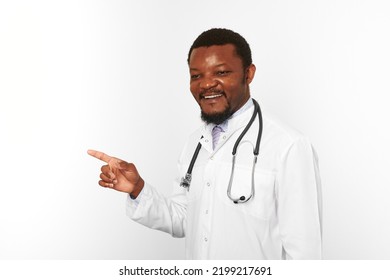 Smiling Black Bearded Doctor Man In White Coat With Stethoscope Points Finger To Left, Isolated On White Background. Adult Black African American Physician Therapist Portrait, Candid Male Emotion