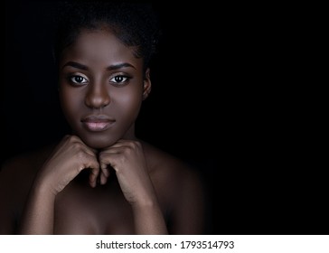 Smiling black beauty on black background, with attractive healthy smooth skin, shiny, clean and pure. Women beauty and make up, black copy space