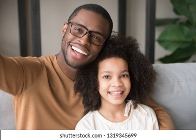 Smiling Black Father And Child Daughter Taking Selfie Together Looking At Camera, Head Shot Portrait Of Happy African Family Dad With Kid Embracing Posing Making Photo Recording Video, Phone Cam View