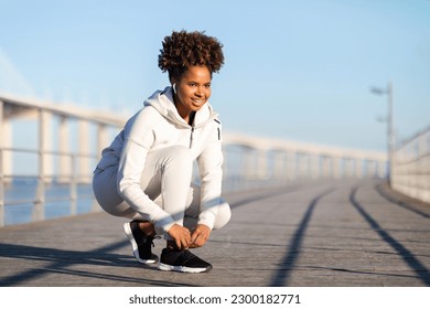 Smiling Black Female Athlete Tying Shoelaces Before Outdoor Training, Young African American Jogger Woman In Sportswear Getting Ready For Morning Run On Pier, Tie Her Lace Shoes, Copy Space - Powered by Shutterstock