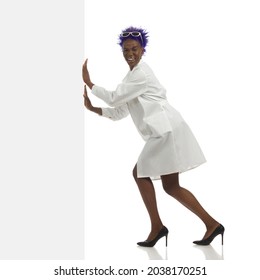 Smiling Black Female Doctor Is Pushing White Banner And Looking At Camera.  Side View. Full Length Studio Shot Isolated On White.