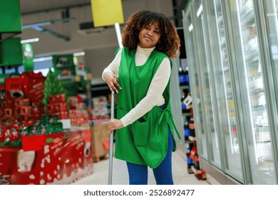 A smiling black female employee in the market is cleaning so that the hygiene of the market is at a high level. - Powered by Shutterstock