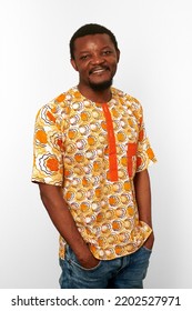 Smiling Black Man In Bright African Clothes Isolated On White Background, Casual African Wear. Happy Bearded Black Guy Portrait With Excited Funny Emotions, Pleasant Man With Hands In Jeans Pockets