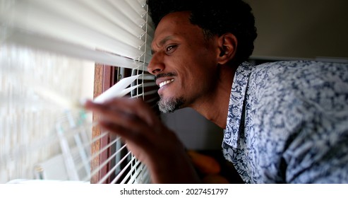 Smiling Black Man Looking Outside Through Window Blinds Feeling Happy