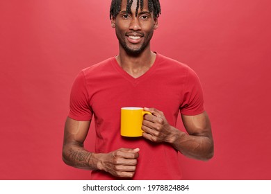 Smiling Black Man In Red T-shirt With A Yellow Mug In Hands On Red Background