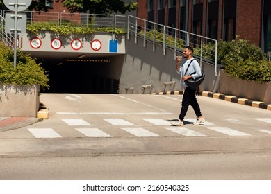 Smiling Black Man Talking On Cell Phone Using Loudspeaker Or Digital Voice Assistant App, Walking Down The Street In The Urban City, Profile Side View, Full Body Length. Positive Guy Speaking Outdoors