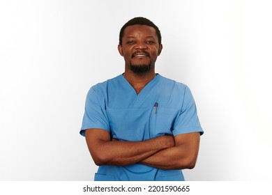 Smiling Black Surgeon Doctor Bearded Man In Blue Coat With Crossed Arms Isolated On White Background. Happy Adult Black African American Practicing Surgeon Portrait, Confident Look