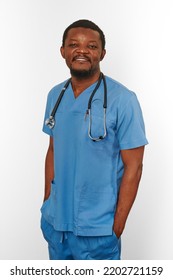 Smiling Black Surgeon Doctor Bearded Man In Blue Coat With Stethoscope Isolated On White Background. Happy Adult Black African American Practicing Surgeon Portrait, Friendly Candid Male Face Emotion