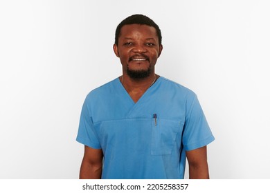 Smiling Black Surgeon Doctor Bearded Man In Blue Coat Isolated On White Background. Happy Adult Black African American Practicing Surgeon Portrait, Friendly Excited Candid Male Face Emotion