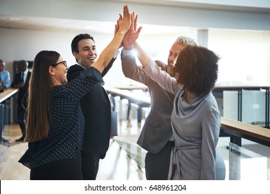 Smiling Black And White Business People Standing In Office And Giving High Five During Teambuilding.