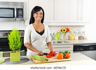 Smiling Black Woman Cutting Vegetables In Modern Kitchen Interior