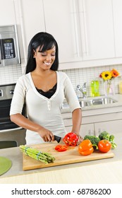 Smiling Black Woman Cutting Vegetables In Modern Kitchen Interior