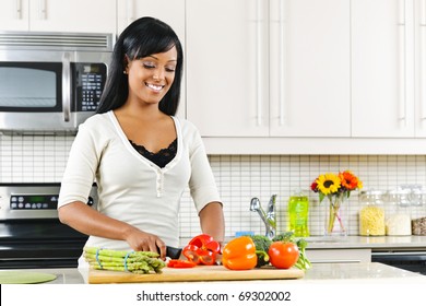 Smiling Black Woman Cutting Vegetables In Modern Kitchen Interior