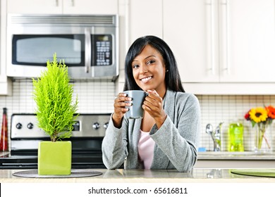 Smiling Black Woman Holding Coffee Mug In Modern Kitchen Interior