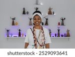 Smiling black woman in white clothing, head cloth and string of beads around her neck