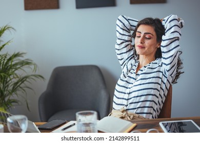 A smiling black-haired woman with headphones and a laptop looking at the screen, a happy young woman listening to her favorite music while working online on a project, an excited woman learning  - Shutterstock ID 2142899511