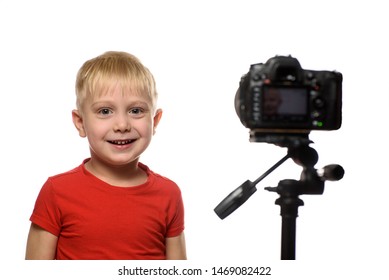 Smiling blond boy in front of the camera lens. Little video blogger. White background