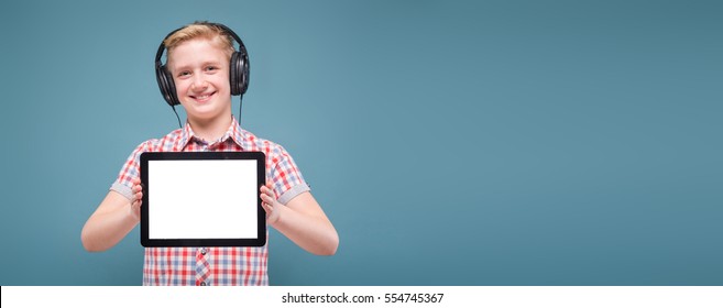 smiling blond student with headphones holding the phone at arm's length and shows the display, the lap studio shot European teenager picture with depth of field, selective focus on phone