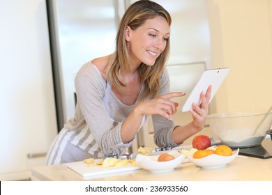 Smiling Blond Woman Looking At Recipe On Digital Tablet