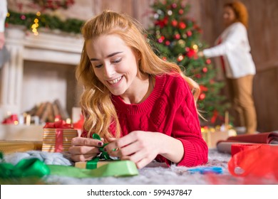 Smiling blonde girl lying on carpet and wrapping gift box - Powered by Shutterstock