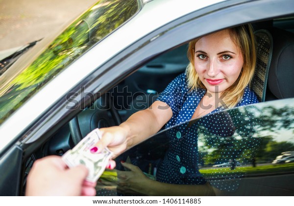 A smiling blonde girl\
offers money a bribe for a fine. Bribe police. Dollars in the hands\
of a girl