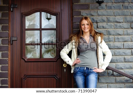 smiling blonde teenager stand near grey brick wall