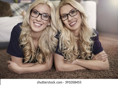 Smiling blonde twins wearing fashion glasses
