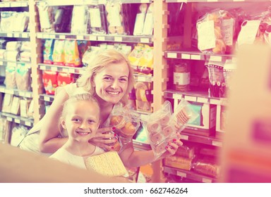 Smiling Blonde Woman With Daughter Buying Various Sweet Cookies In Grocery Store
