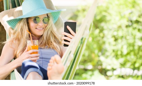 Smiling blonde woman with sunglasses using smartphone, relaxing on the hammock in garden, drinks a juice, free time and summer holiday concept for surf internet or chat with friends using social media - Powered by Shutterstock