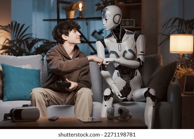Smiling boy and AI robot playing video games together at home they are friends and giving a fist bump