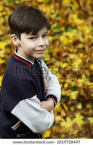 Smiling Boy in Autumn Jacket Surrounded by Colorful Fall Leaves