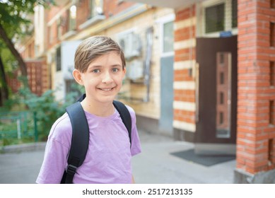 Smiling boy with backpack standing in front of the entrance of the house