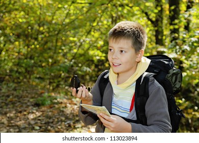 Smiling boy with compass and map orienteering in forest - Shutterstock ID 113023894