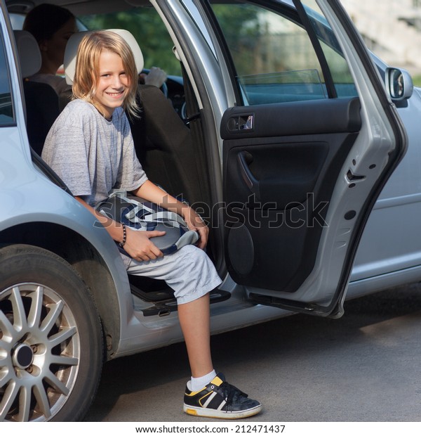 Smiling\
boy getting out of the car on his way to\
school.
