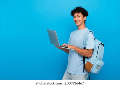 Smiling boy guy high school male pupil student teenager with backpack holding using laptop computer for distant studding ,e-learning doing homework online isolated in blue background copy space - Powered by Shutterstock