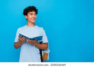 Smiling boy guy high school male pupil student teenager with bag holding open books copybooks isolated on blue background looking empty copy space for advertisement. Education back to school concept - Powered by Shutterstock