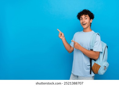 Smiling boy guy high school male pupil student teenager with dental braces backpack pointing index finger empty copy space advertisement isolated on blue background. Education back to school concept - Powered by Shutterstock