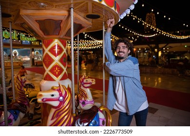A smiling boy leans on a carousel at the sideshows during christmas