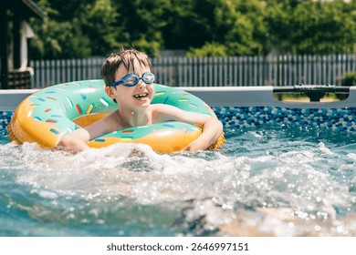 Smiling boy in pool float with blue goggles enjoying fun summer day in backyard swimming pool