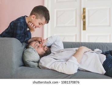 Smiling Boy Wakes Up A Father Who Fell Asleep On The Couch.